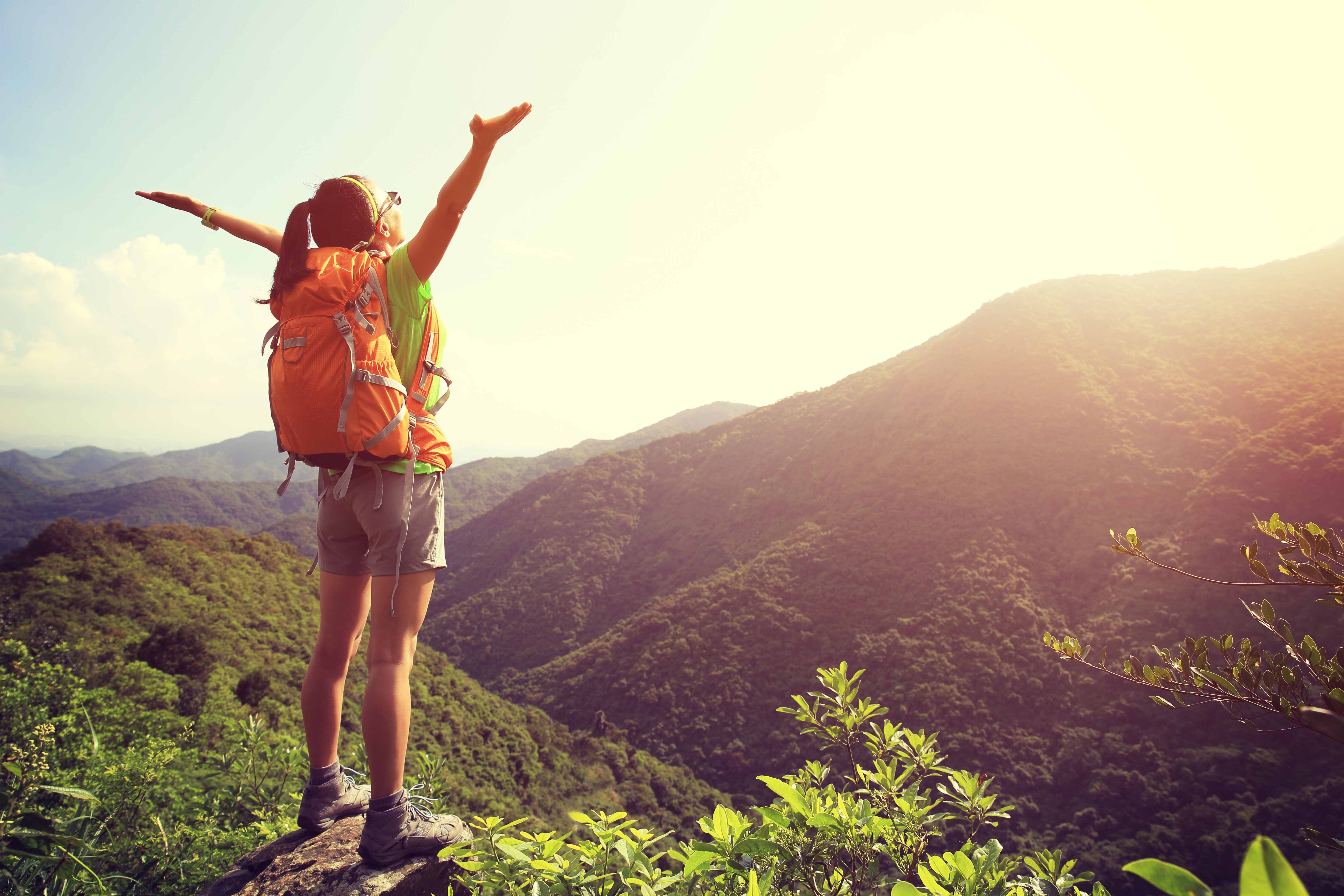 woman backpacker cheering on cliff